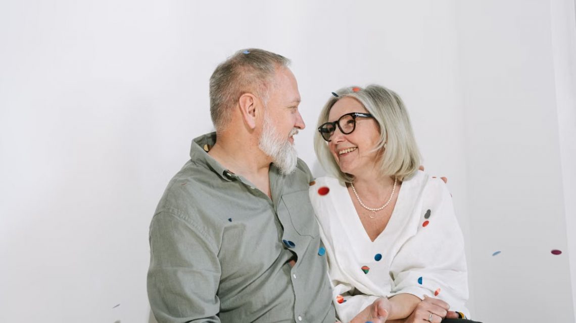 Senior couple enjoying a joyful moment with confetti indoors, portraying happiness and love.